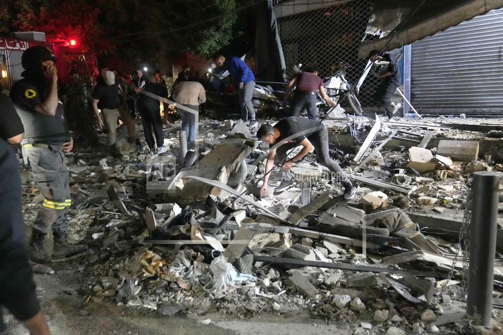 People clear debris from the street in a residential neighborhood of Beirut, Lebanon, after an Israeli attack — Foto: Hussein Malla/AP